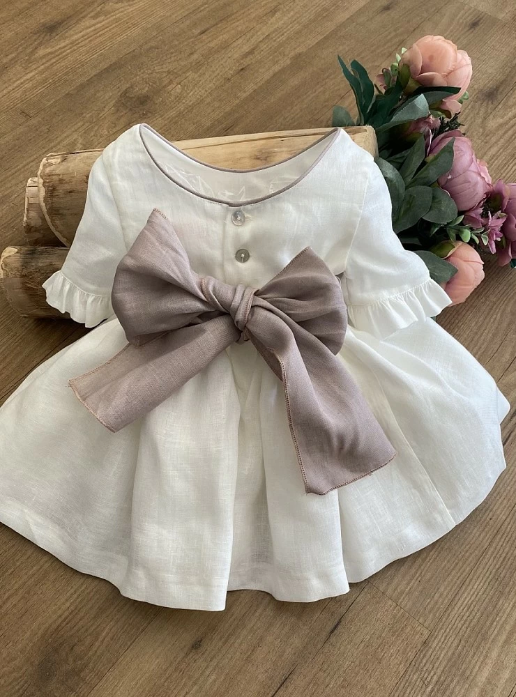 Ecru linen dress with bow and mauve flowers.