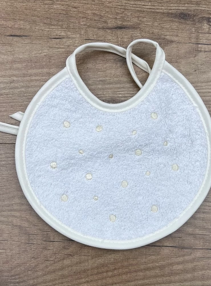 Round terry cloth bib. She wears embroidered bodoques