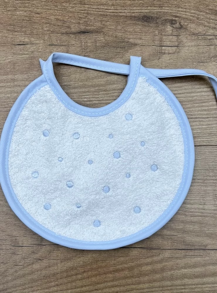 Round terry cloth bib. She wears embroidered bodoques